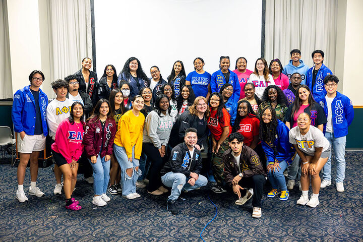 A group of students wearing greek-letter sweatshirts and jackets poses for the camera.